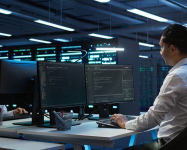 Engineers in high tech data center establishment installing software on computer, troubleshooting issues. Team of IT specialists in server room establishing performance benchmarks